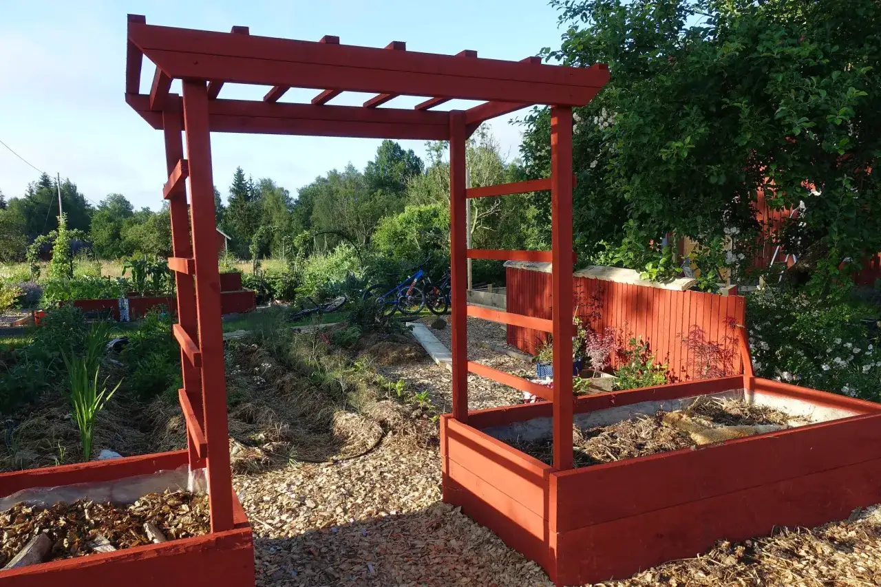 En röd träpergola med en blomlåda. En ritning för att bygga blomlåda kan ha sett ut så här.