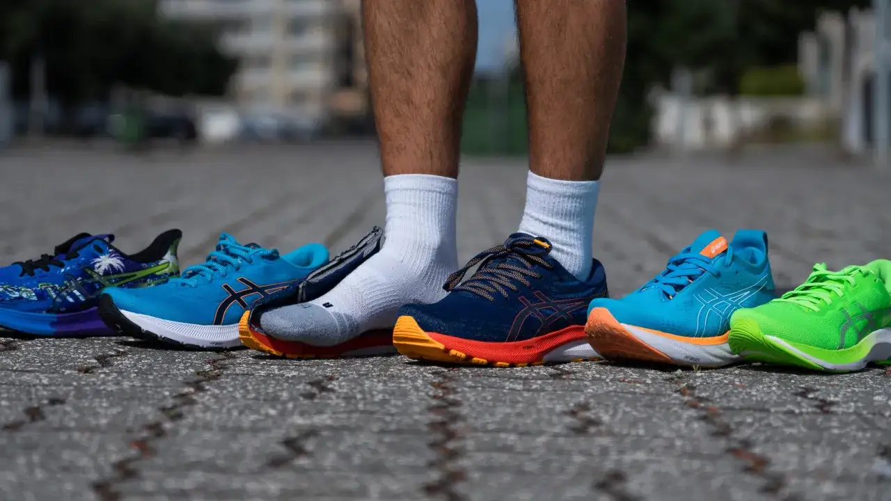 Biegacz prezentuje buty Asics, znanej firmy sportowej, w różnych kolorach i wzorach.