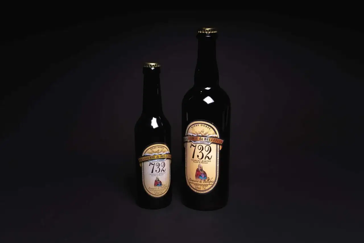 Deux bouteilles de bi&egrave;re dor&eacute;e de la Brasserie de Bellefois, l'une plus petite que l'autre, se dressent sur un fond sombre.