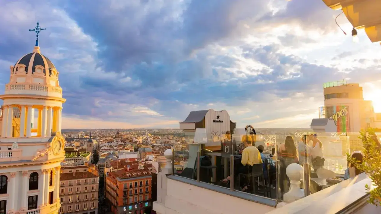 Disfruta de unas **terrazas azoteas Madrid baratas** con vistas espectaculares al atardecer. Gente relajada en un bar en la azotea.