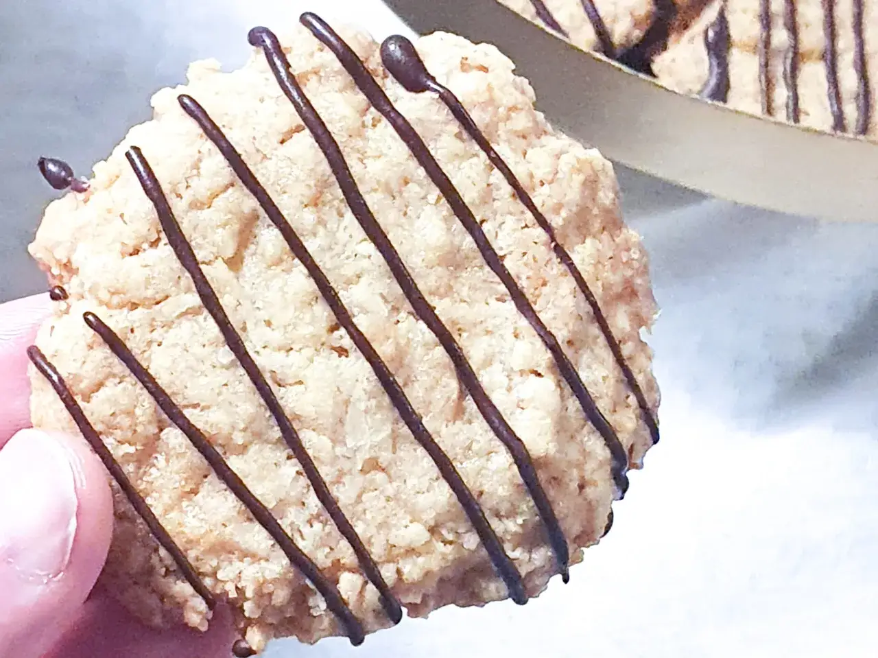 En hand håller en chokladglaserad havrekaka. Perfekt för ett enkelt havrekakor recept.
