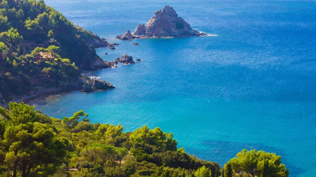 Vista mozzafiato di una località balneare in provincia di Grosseto, con scogliere verdi e mare cristallino.
