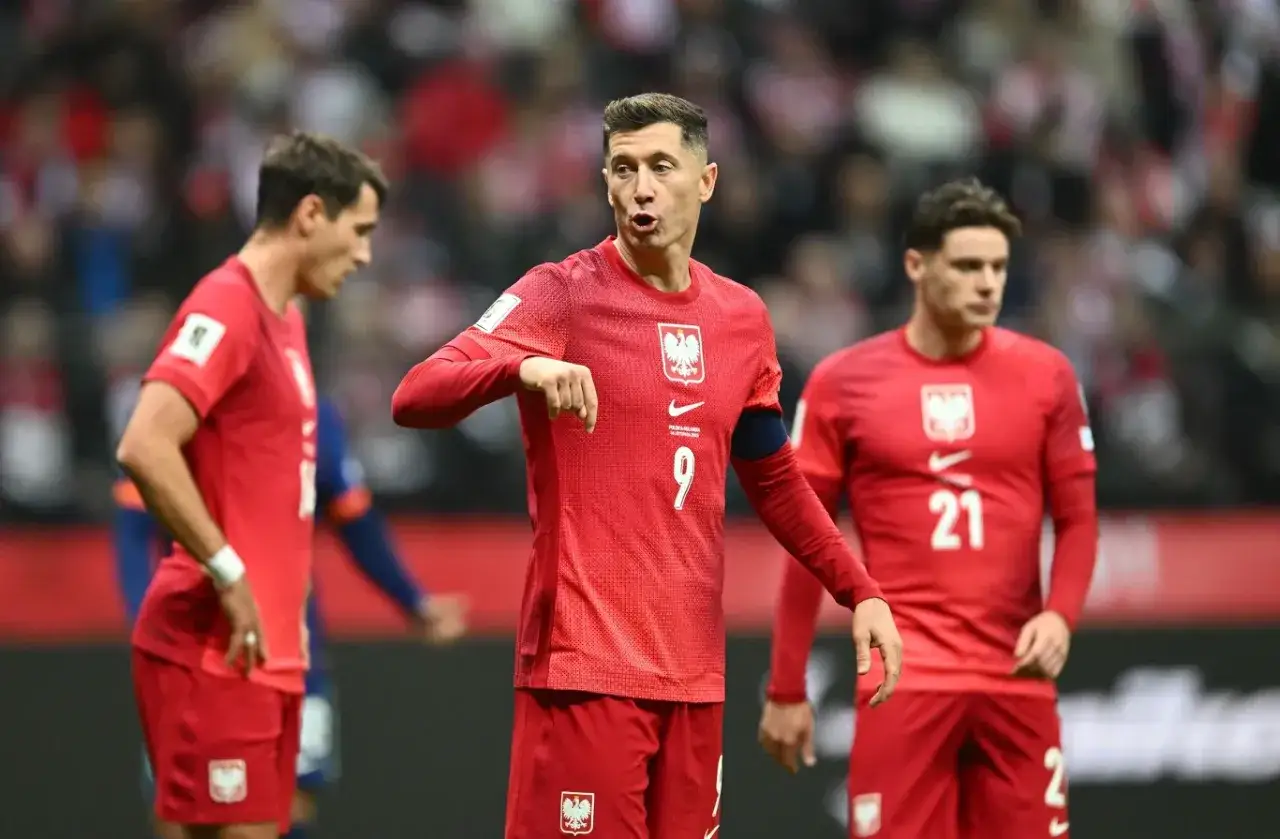 Piłkarze reprezentacji Polski w czerwonych strojach, gotowi do gry. Robert Lewandowski z numerem 9 na koszulce, w emocjonującym momencie meczu.