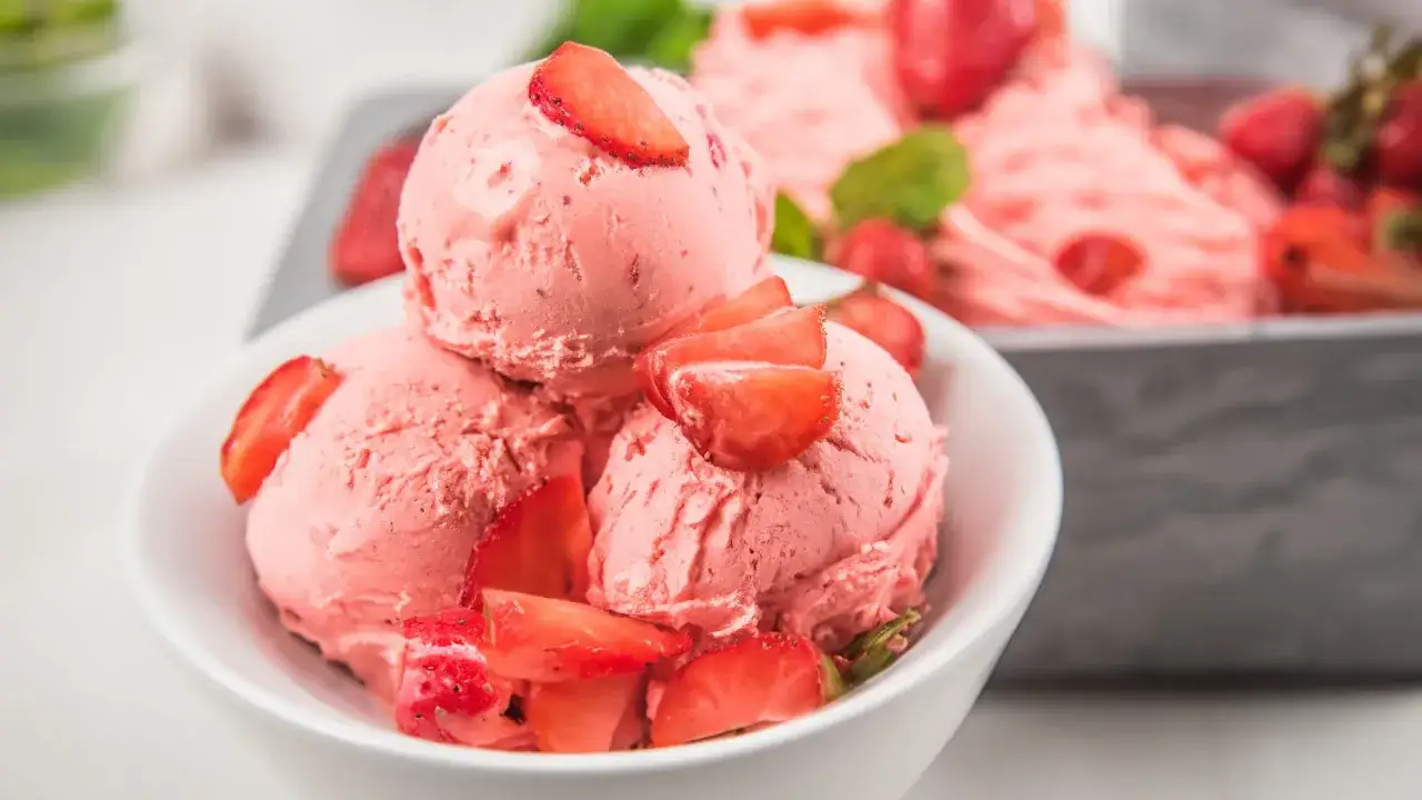 Pyszne, różowe lody truskawkowe z kawałkami owoców. Czy lody są lekkostrawne? Ten deser wygląda na idealny na upalne dni.