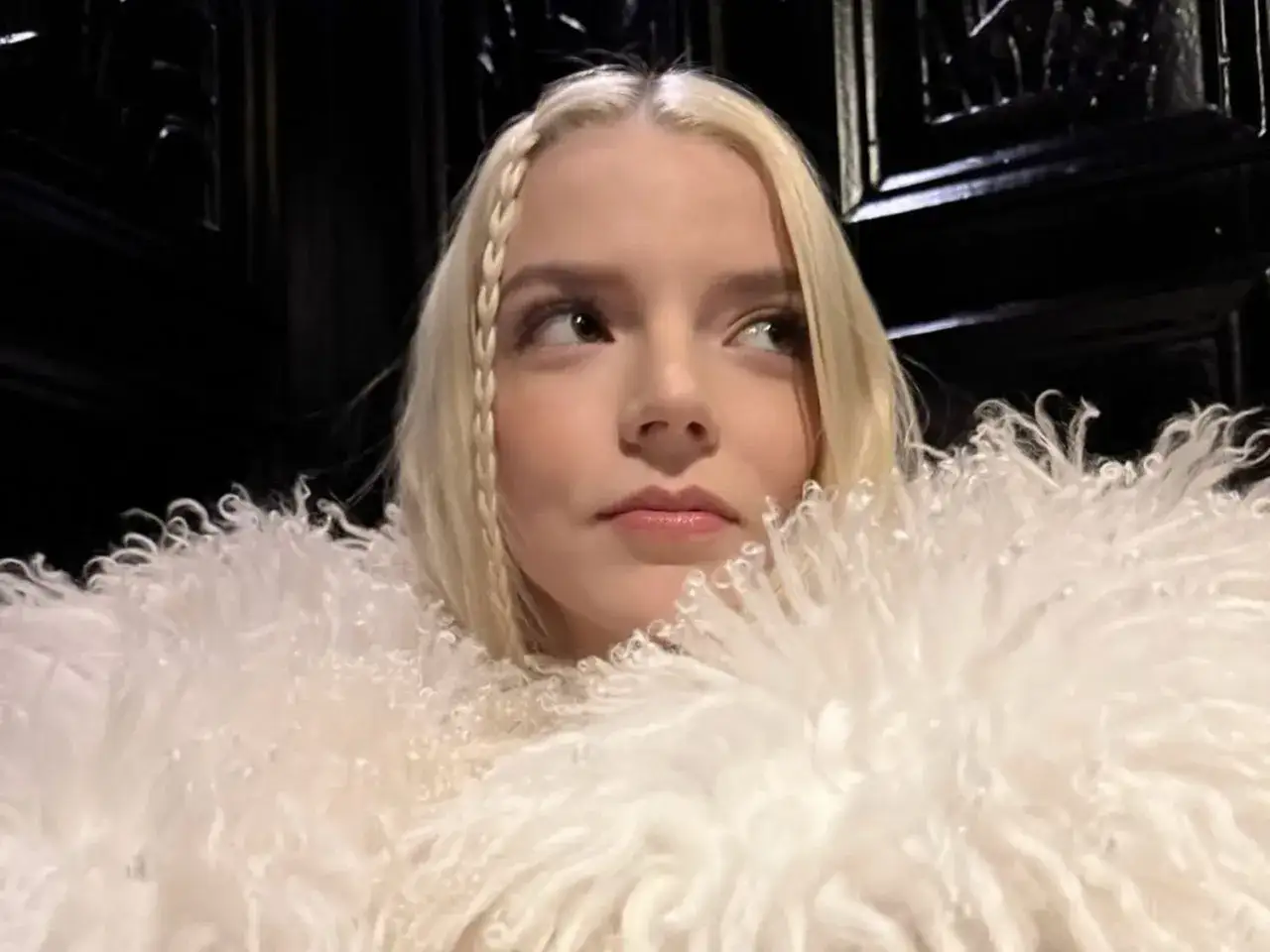 Ragazza con splendidi capelli platino, una treccia laterale e un cappotto bianco di pelliccia.