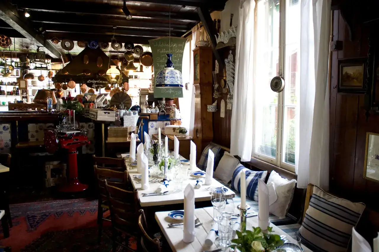 Gemütliches Ambiente mit gedeckten Tischen, Kupfergeschirr und einer Speisekarte, die auf die besten Restaurants in Bergisch Gladbach hindeutet.