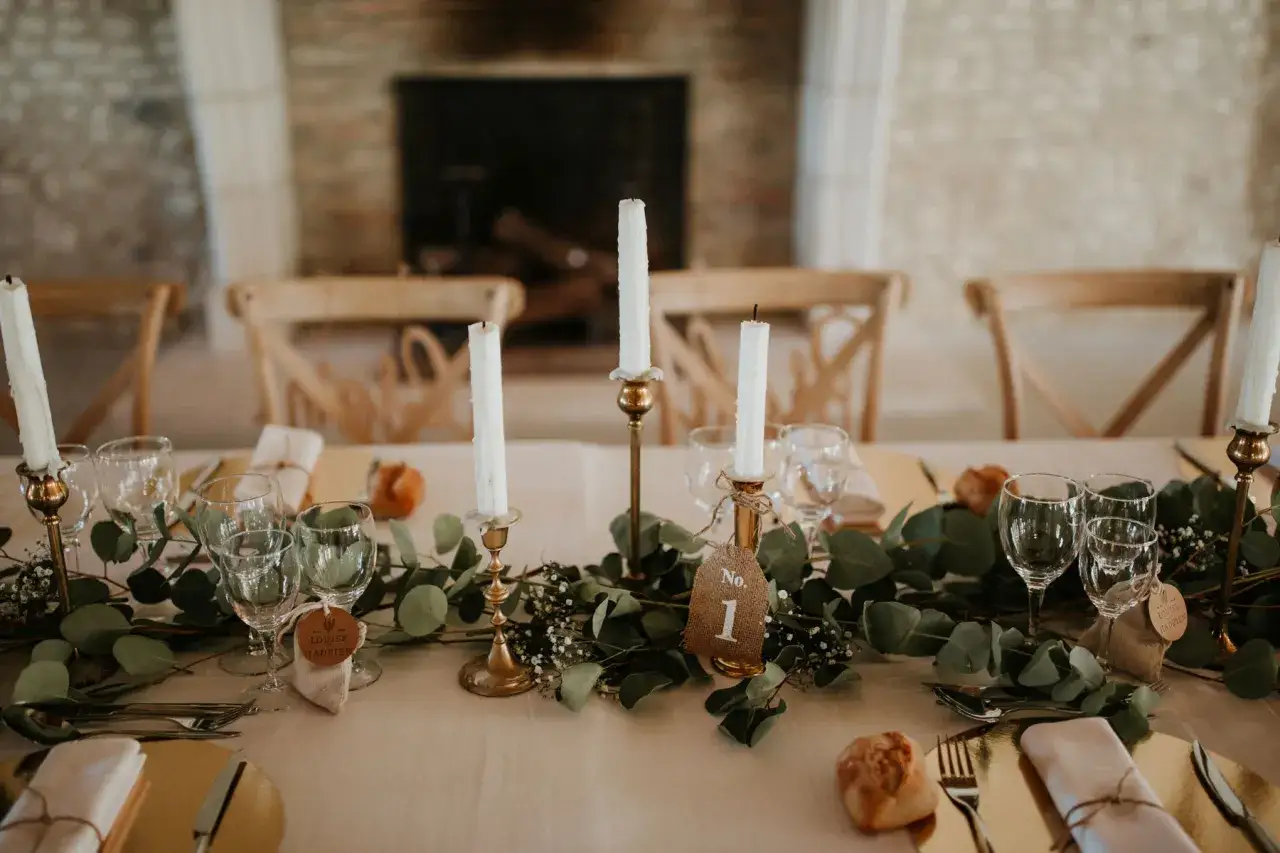 D&eacute;coration de table pour un mariage simple et original : bougies, verres, eucalyptus et petits pains.
