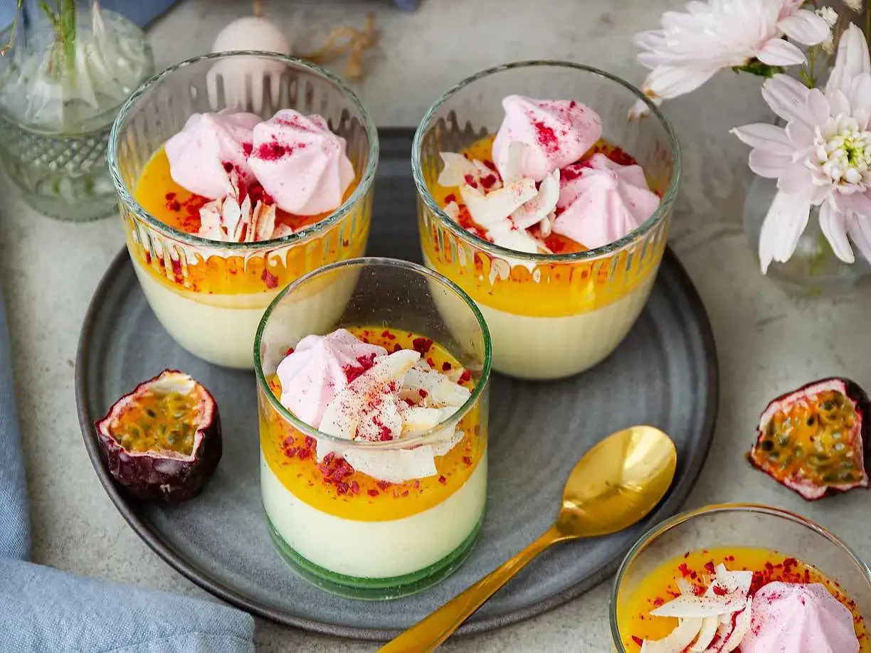 Vackra glas med pannacotta p&aring;sk, toppade med passionsfruktscurd, rosa mar&auml;ng och kokosflingor. En festlig dessert!
