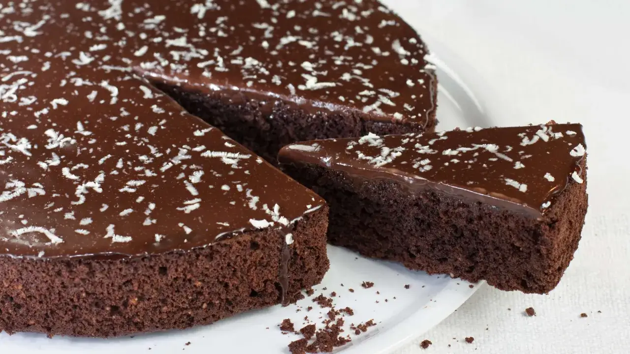 Ein St&uuml;ck saftiger Schokokuchen mit gl&auml;nzender Schokoladenglasur und Kokosraspeln.