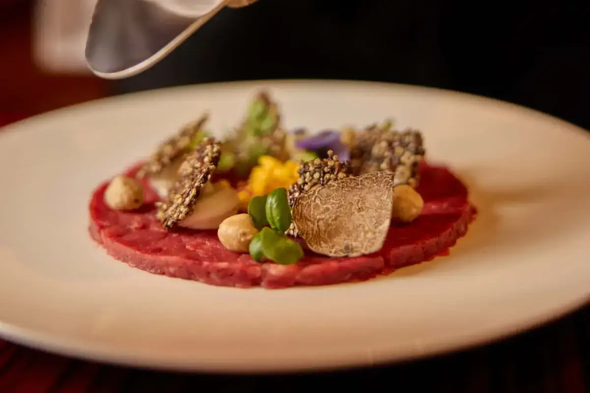 Carpaccio di manzo con tartufo, nocciole e fiori eduli, un perfetto abbinamento barolo per un'esperienza gourmet.