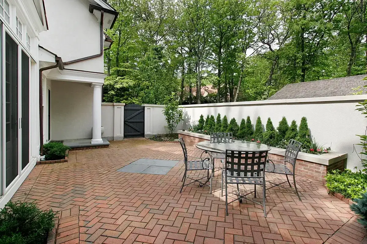 Patio z cegły, stary mur z cegły w ogrodzie, stół i krzesła.