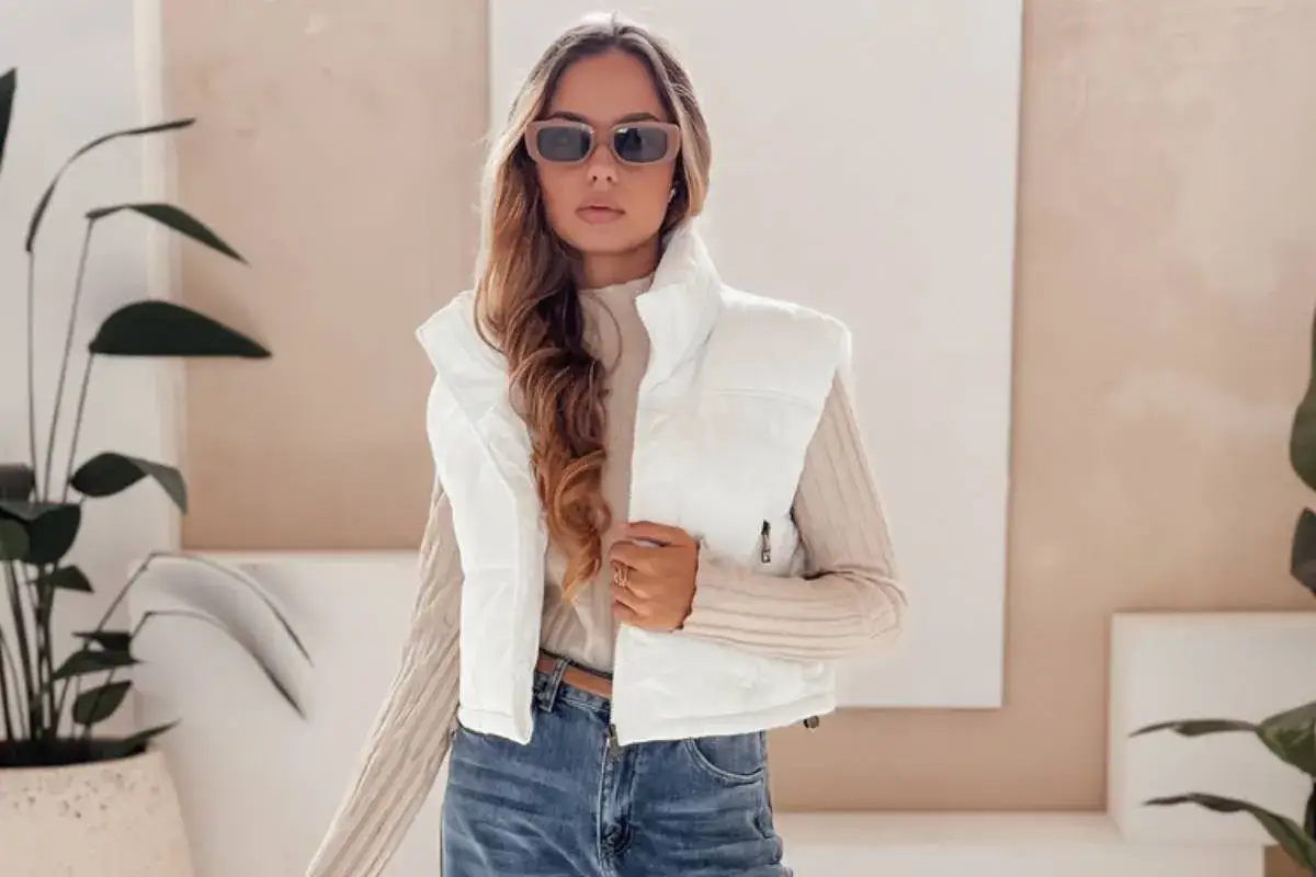 Stylowa kobieta w białej kamizelce damskiej i jeansach. Inspiracja, jak nosić kamizelkę damską na co dzień.