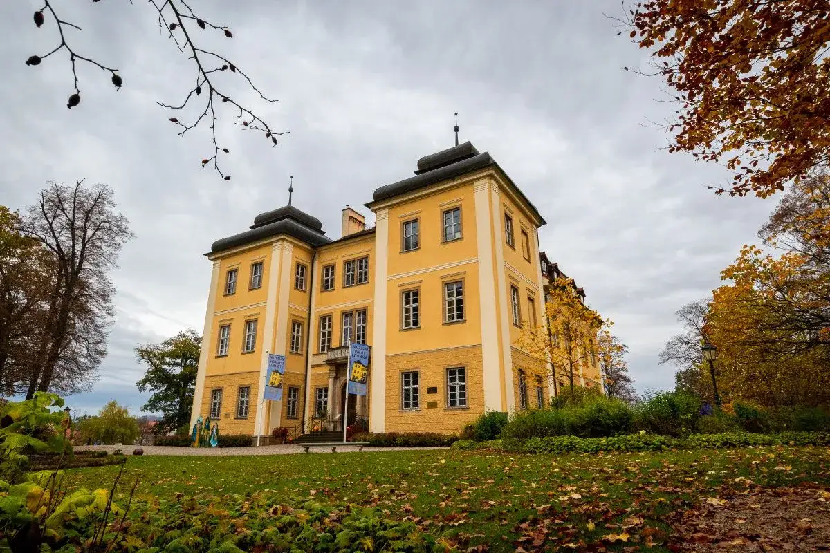 Ż&oacute;łty pałac otoczony jesienną przyrodą, idealne miejsce na romantyczne spacery po Dolnym Śląsku.