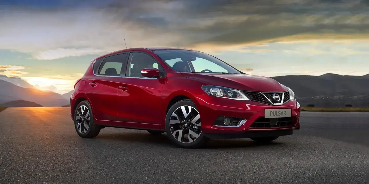 Czerwony Nissan Pulsar na tle górskiego krajobrazu o zachodzie słońca. Poznaj jego wymiary i możliwości.
