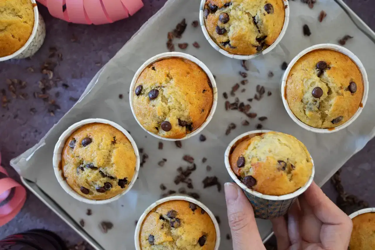Frisch gebackene bananen muffins mit Schokostückchen, auf einem Blech mit Backpapier, bereit zum Genießen.