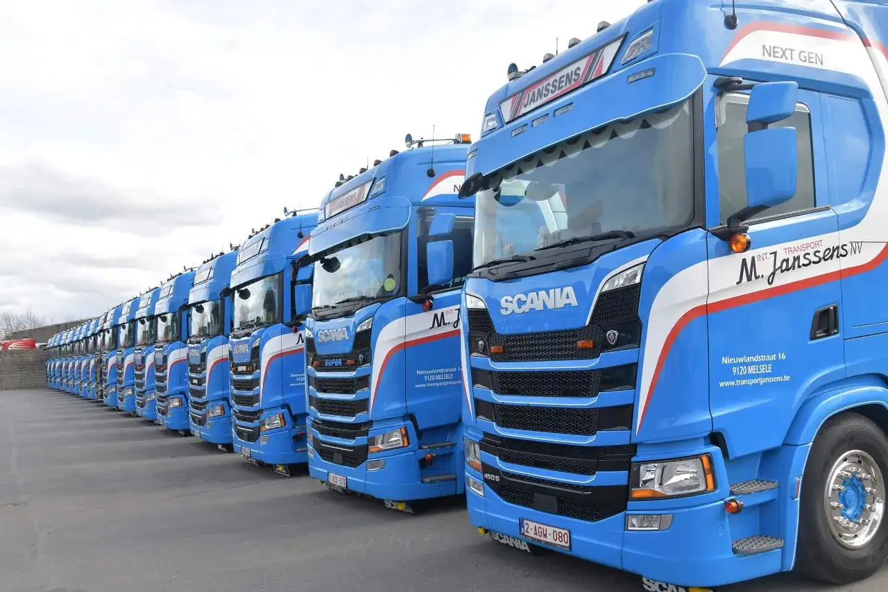Une longue rang&eacute;e de camions bleus Scania, tous mod&egrave;les v8 camion, align&eacute;s sur un parking.