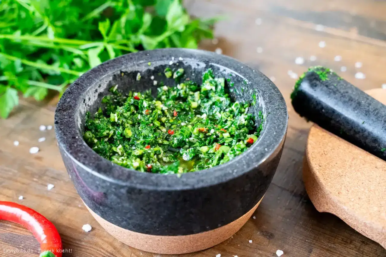 Frische Kr&auml;uter, Chili und &Ouml;l &ndash; die chimichurri hauptzutaten werden im M&ouml;rser zubereitet.