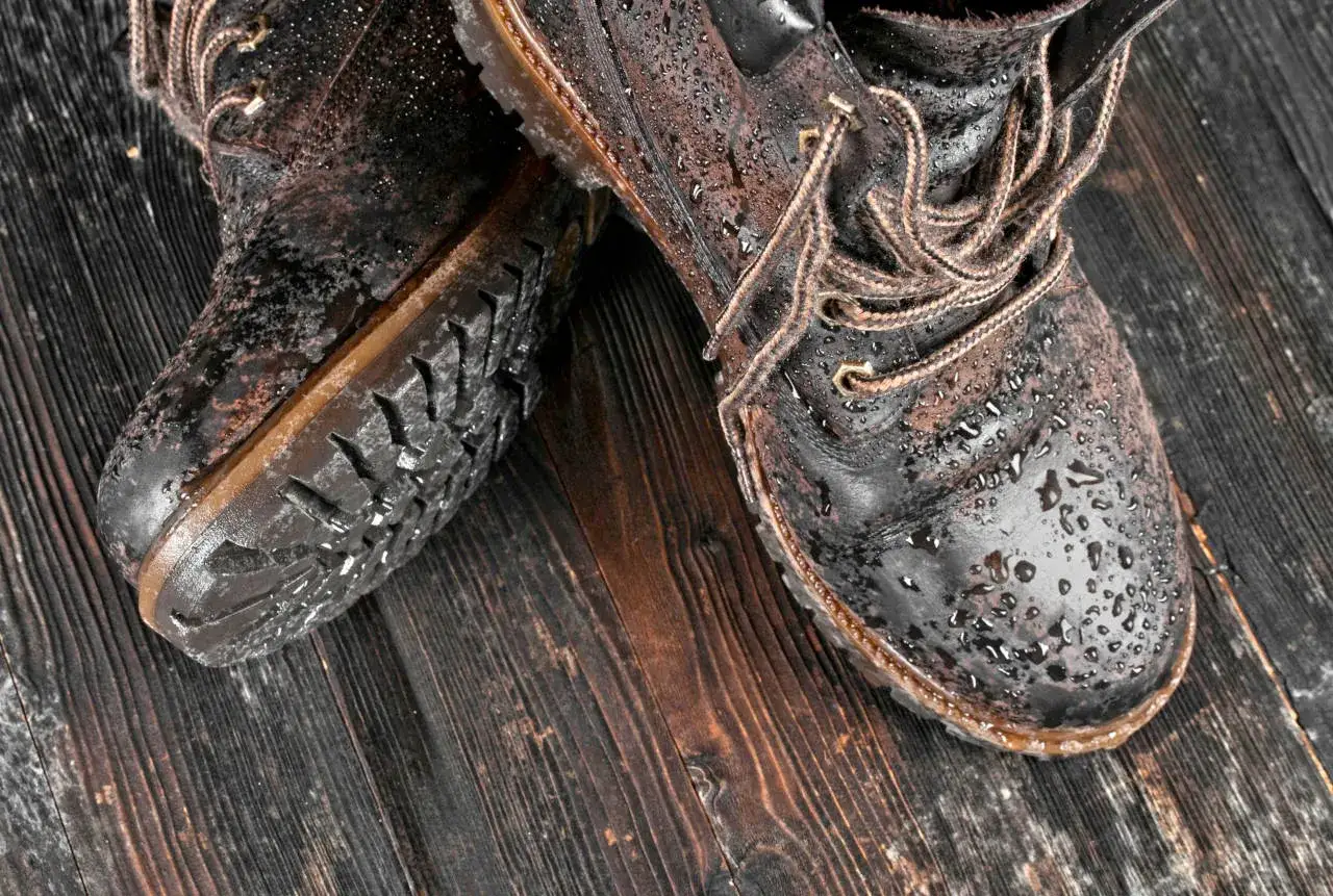 Bottes en cuir mouillées sur fond de bois. Apprenez comment sécher des baskets rapidement pour les remettre en état.