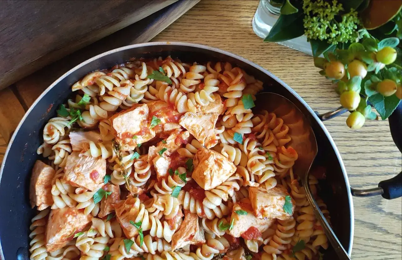 Délicieuses pâtes au poisson italiennes, fusilli avec des morceaux de poisson et sauce tomate, garnies de persil frais.
