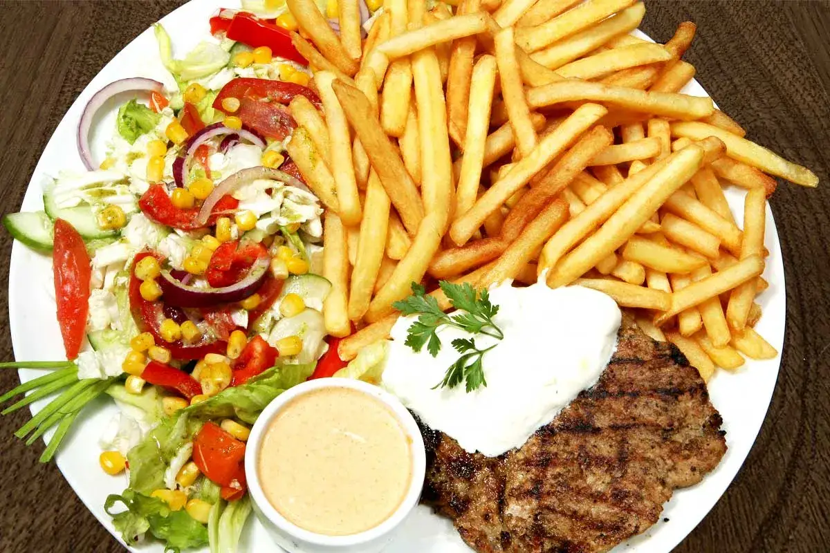 Talerz z grillowanym kotletem, frytkami, sałatką i sosem. Idealne na letnie wieczory, te sprawdzone przepisy na grilla zachwycą każdego!