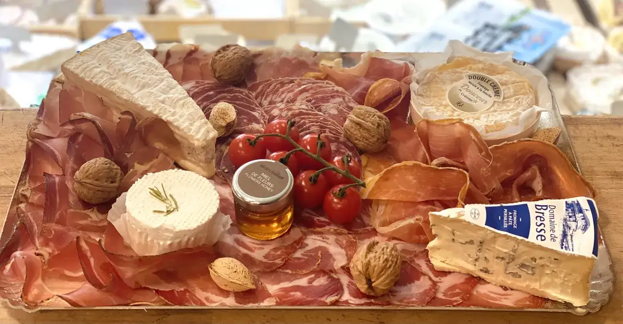 Plateau de charcuterie et fromages vari&eacute;s : jambon, saucisson, brie, fromage bleu, ch&egrave;vre frais, tomates cerises, noix, amandes et miel. Parfait pour savoir quoi manger avec de la charcuterie.