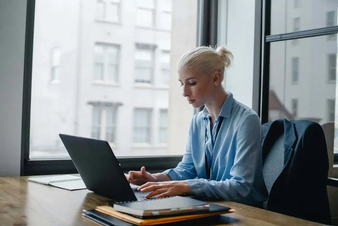 Donna bionda lavora al laptop, analizzando dati per ottimizzare lo stipendio dell'e-commerce manager.