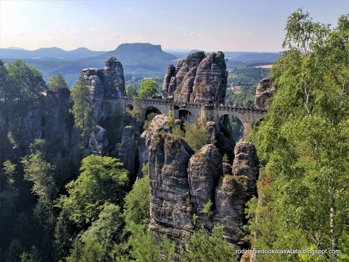 Kamienny most Basteibrücke w Szwajcarii Saksońskiej, łączący skalne baszty pośród zielonych lasów i gór.
