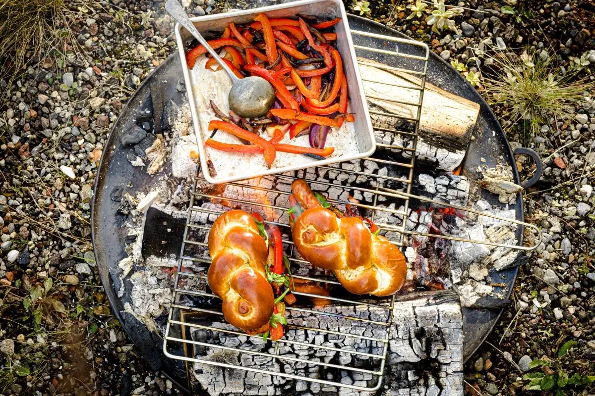 Deux pains tress&eacute;s dor&eacute;s pr&ecirc;ts pour un barbecue hot dog, avec des poivrons grill&eacute;s &agrave; c&ocirc;t&eacute;.