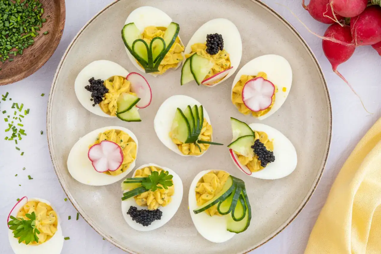 Köstliche deviled eggs deutsch, garniert mit Gurke, Radieschen und Kaviar, auf einem Teller arrangiert.