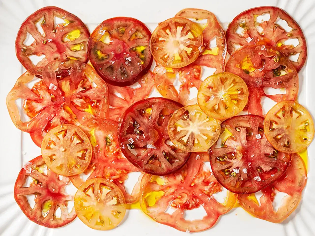 Rodajas de tomate fresco, rociadas con aceite y sal, formando un delicioso carpaccio de tomate.