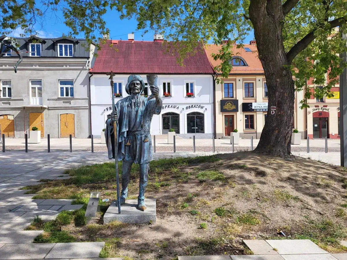 Pomnik pielgrzyma z kielichem i laską na tle kamienic. Idealne miejsce na weekendowe zwiedzanie, odkryj częstochowa atrakcje na weekend.