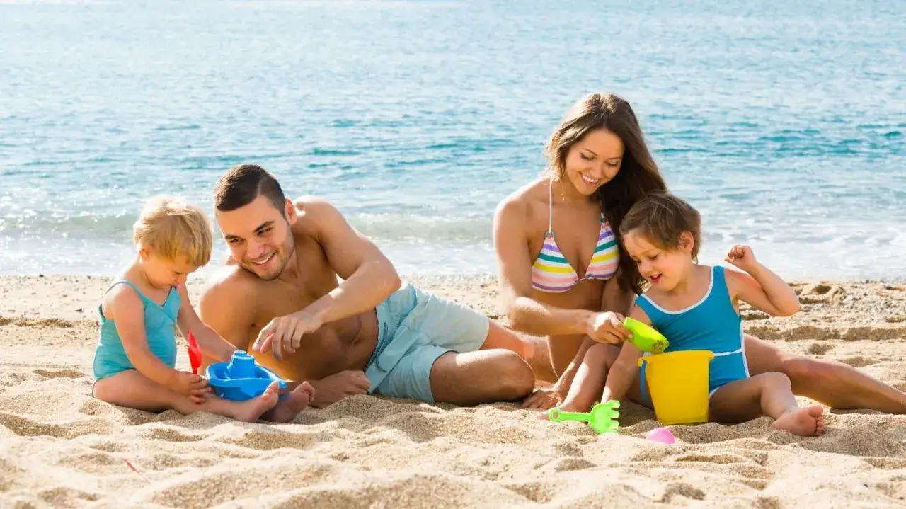 Familia feliz disfrutando de la Riviera Maya con niños, jugando en la arena y el mar.