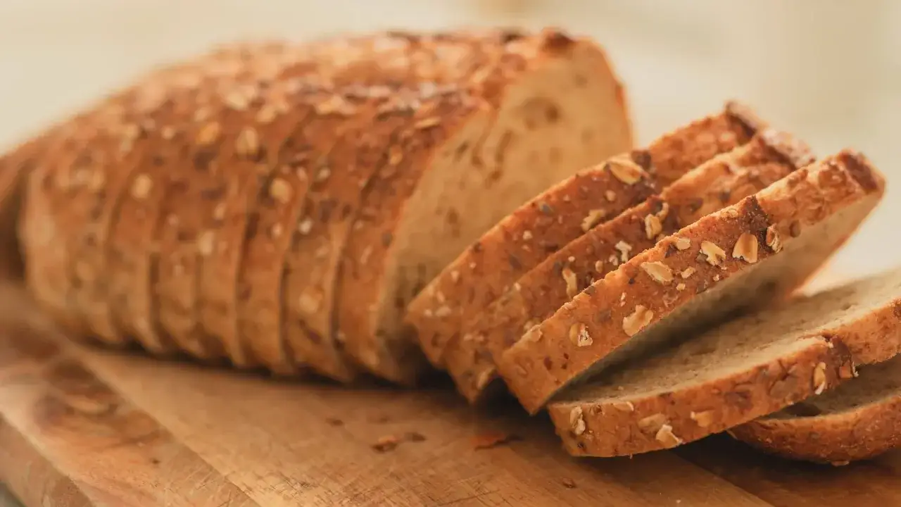 Frisch gebackenes Brot mit Körnern, perfekt zum Brot backen im Airfryer. Die Scheiben liegen auf einem Holzbrett.
