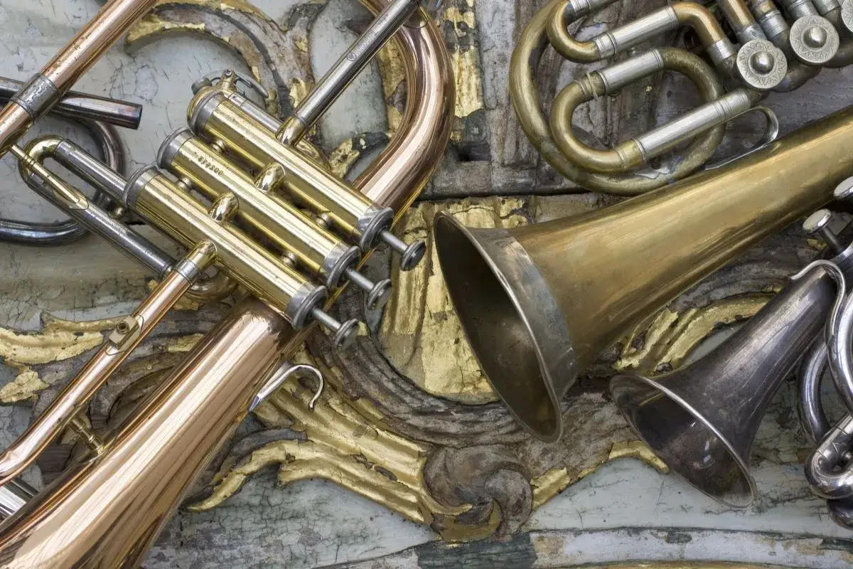 Złote i srebrne blaszane instrumenty dęte, w tym trąbka i r&oacute;g, leżą na ozdobnej, złoconej powierzchni.