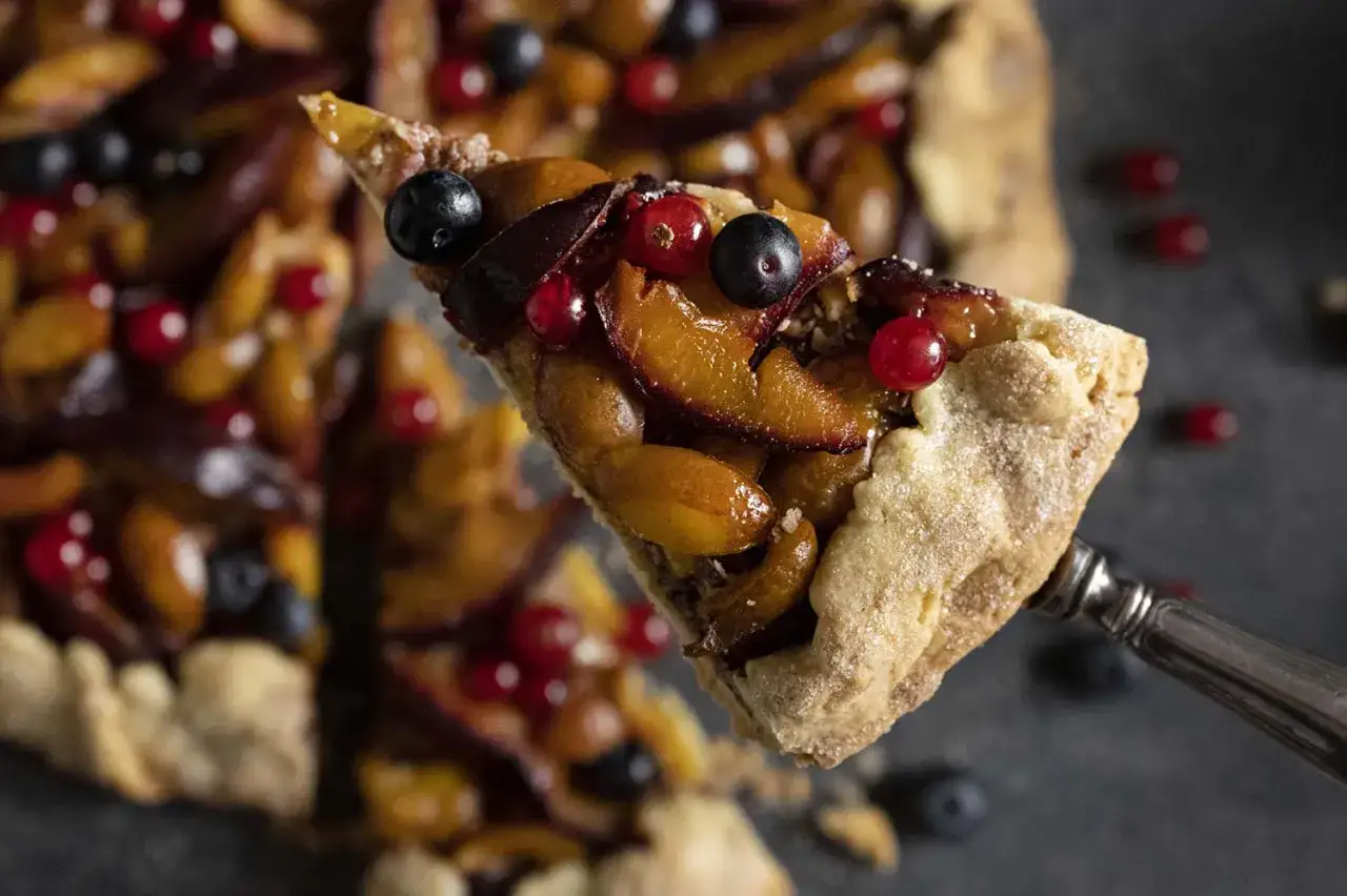 Ein Stück saftige Zwetschgen-Galette mit Beeren, perfekt für ein einfaches galette rezept.