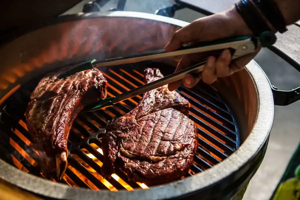 Deux belles c&ocirc;tes de b&oelig;uf sur un barbecue &agrave; gaz, pr&ecirc;tes pour le temps de cuisson id&eacute;al. La viande gr&eacute;sille sur les braises ardentes.