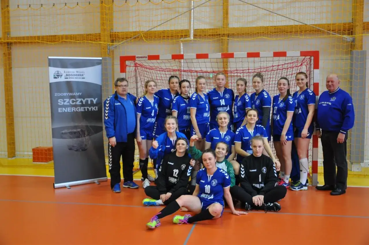 Drużyna MKS Lublin w strojach sportowych pozuje do zdjęcia z trenerami.