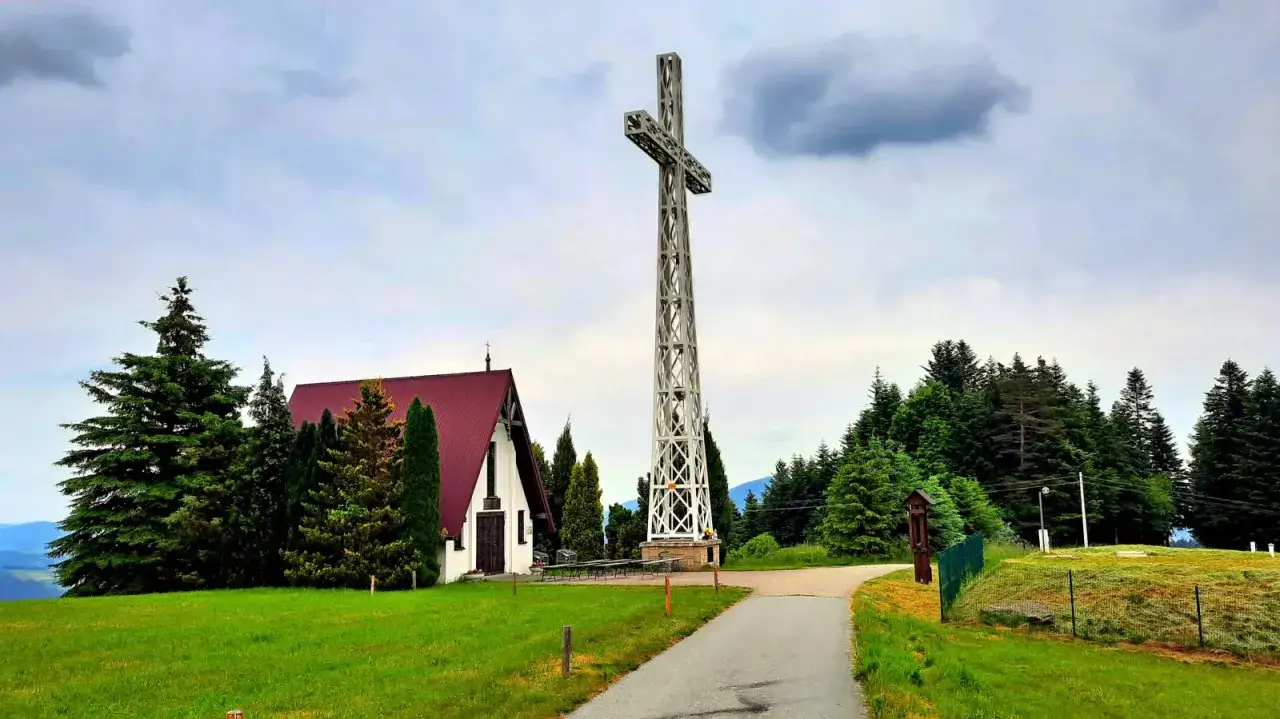 Wielki metalowy krzyż góruje nad kościołem i zielonymi wzgórzami w Tymbarku.