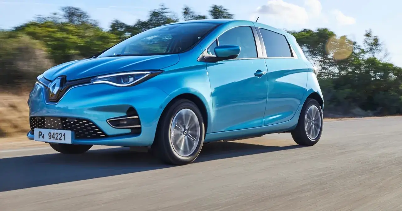 Błękitny Renault Zoe jedzie po drodze, pokazując swój imponujący zasięg.