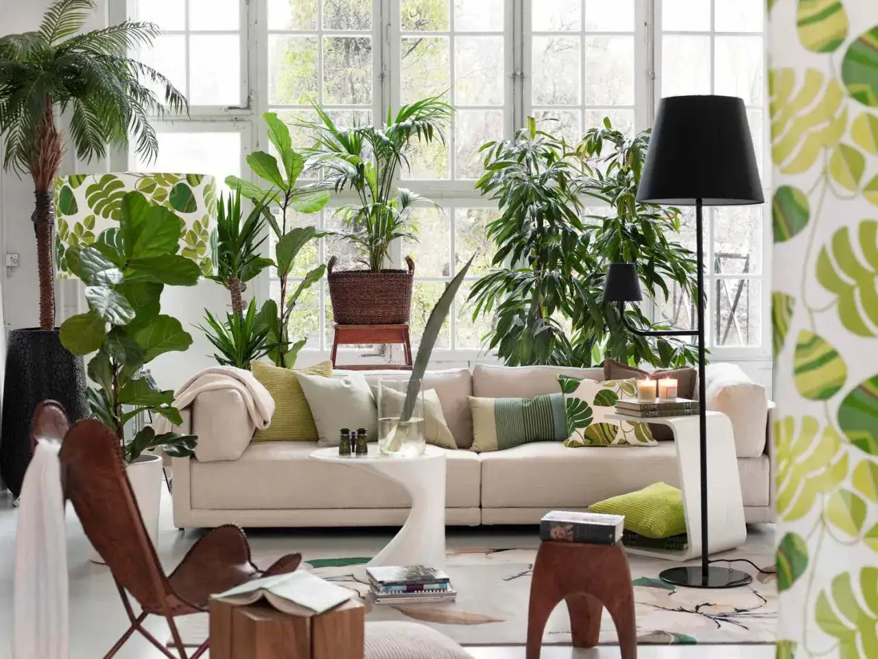 En ljus och luftig lounge med tropisk inredning. Palmer och gr&ouml;na v&auml;xter skapar en frodig atmosf&auml;r. En bekv&auml;m soffa och en l&auml;derf&aring;t&ouml;lj inbjuder till avkoppling.
