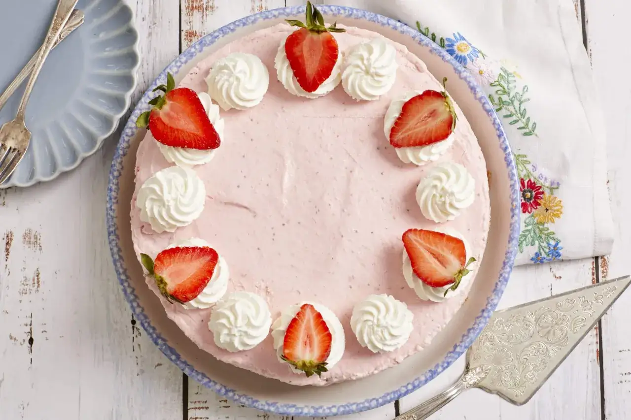 Ein köstlicher Erdbeerkuchen ohne Backen, verziert mit frischen Erdbeeren und Sahnetuffs, wartet darauf, serviert zu werden.