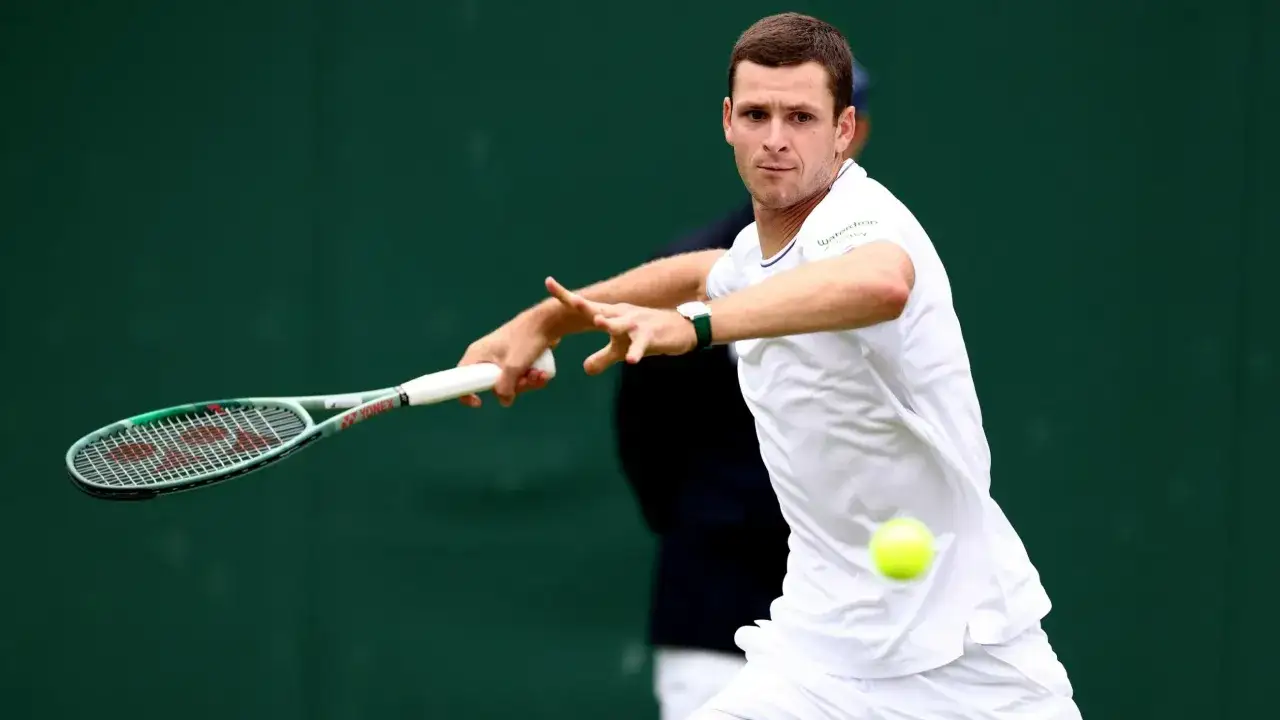 Hubert Hurkacz w akcji na Wimbledonie, uderza piłkę rakietą.