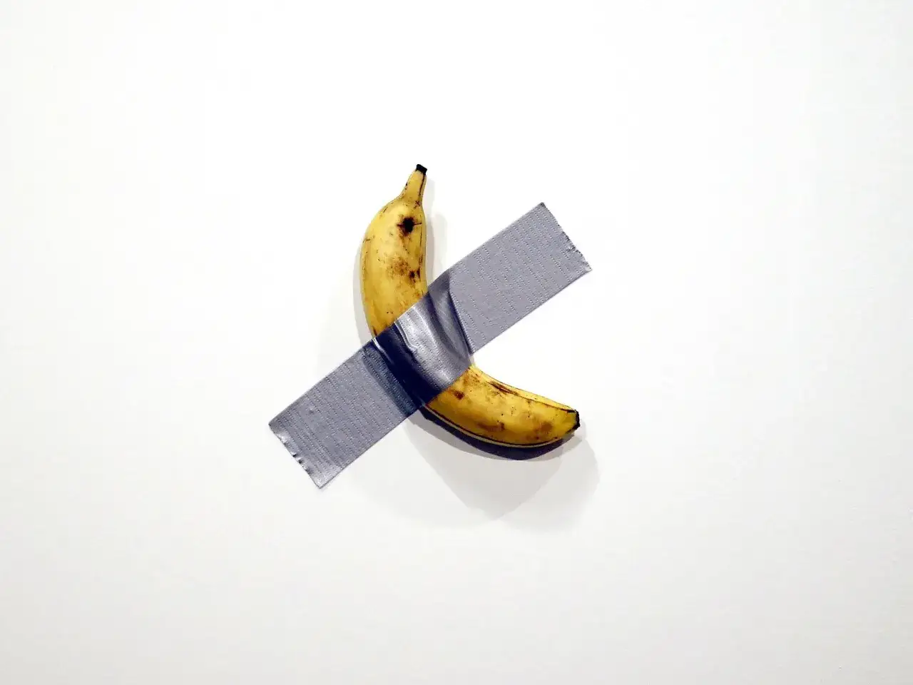 Une banane, &oelig;uvre de Maurizio Cattelan, fix&eacute;e au mur avec du ruban adh&eacute;sif gris.