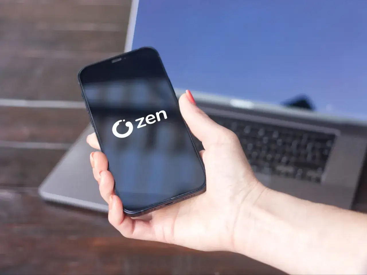 Dłoń trzyma smartfon z logo Zen. To idealne narzędzie do zarządzania Twoim kontem Zen.