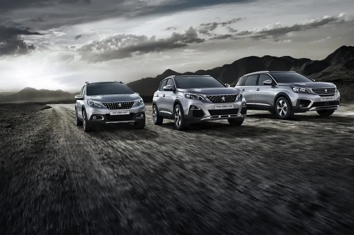 Trzy eleganckie modele peugeot suv pędzą po kamienistej drodze, w tle górzysty krajobraz i dramatyczne chmury.