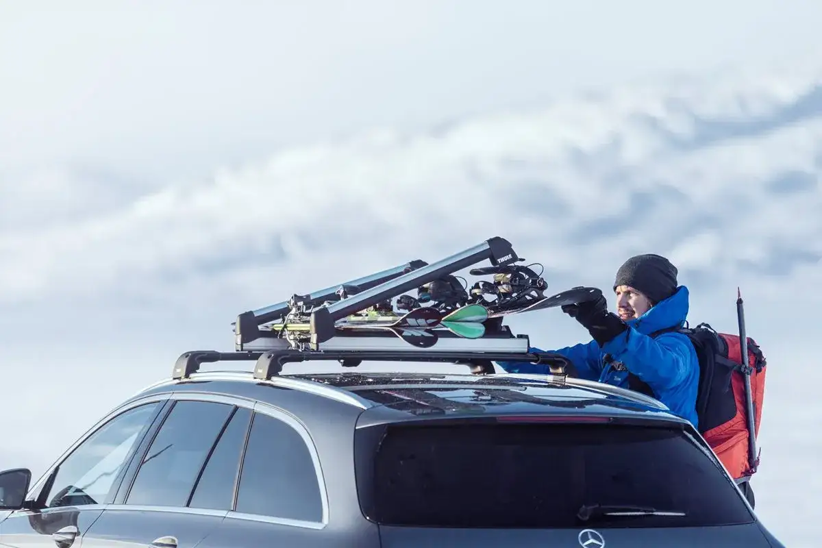 Man lastar l&auml;ngdskidor i en takbox p&aring; en bil, redo f&ouml;r en tur i sn&ouml;iga berg.