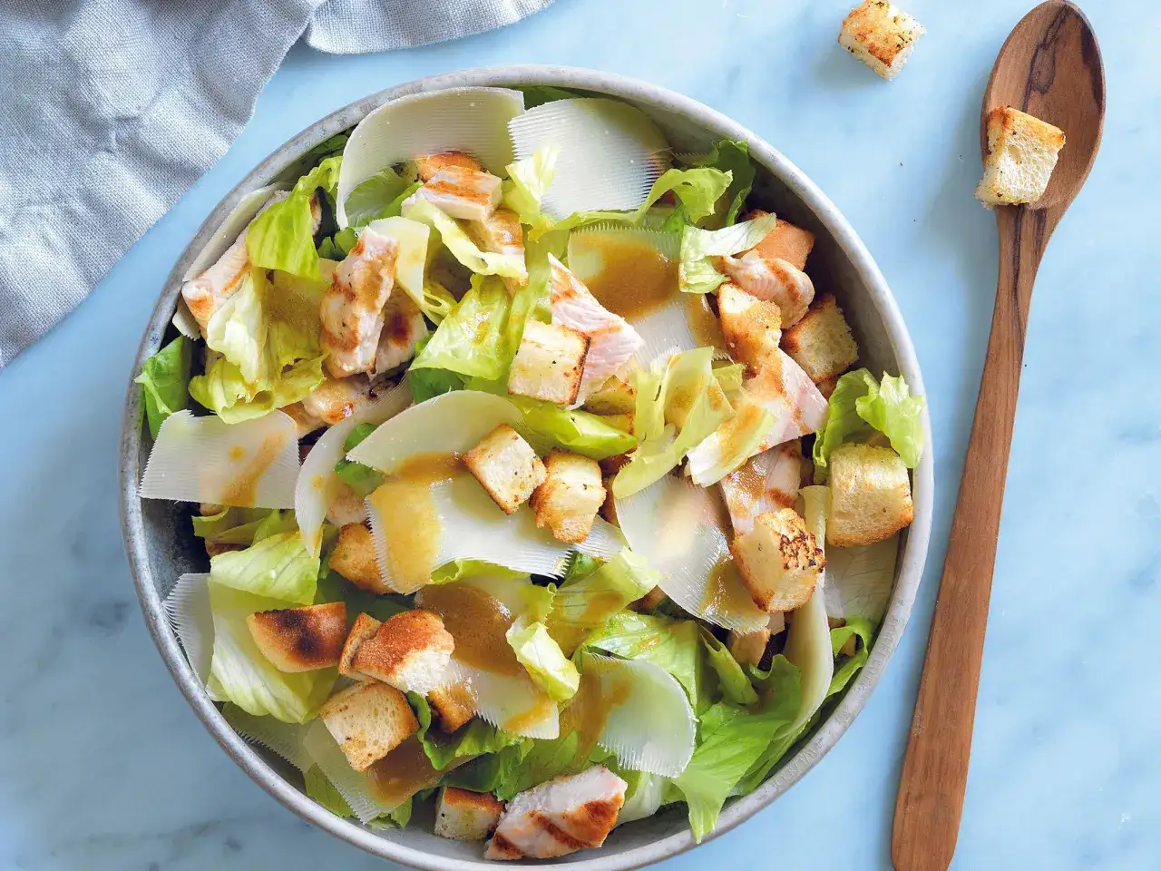 Insalata di pollo lesso con crostini dorati, scaglie di parmigiano e lattuga fresca, condita con una vinaigrette.