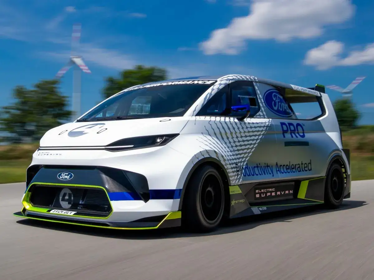 Der Ford Supervan rast auf einer Straße, mit Windrädern im Hintergrund.