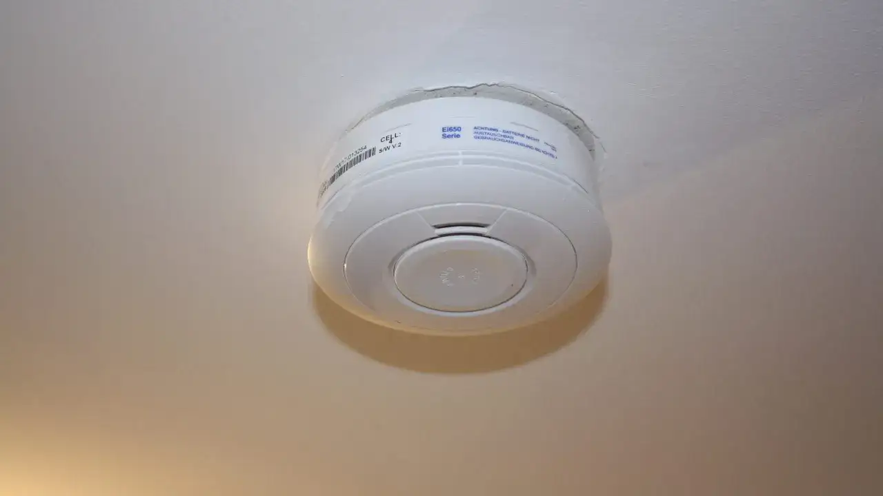 Ein weißer Rauchmelder an der Decke, bereit, bei Gefahr einen Alarm auszulösen.