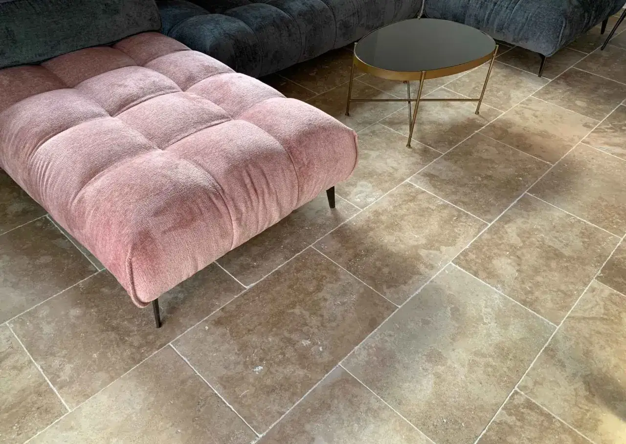 Un canapé rose et un fauteuil gris sur un sol en pierre naturelle. Le traitement pierre met en valeur la beauté authentique des dalles.